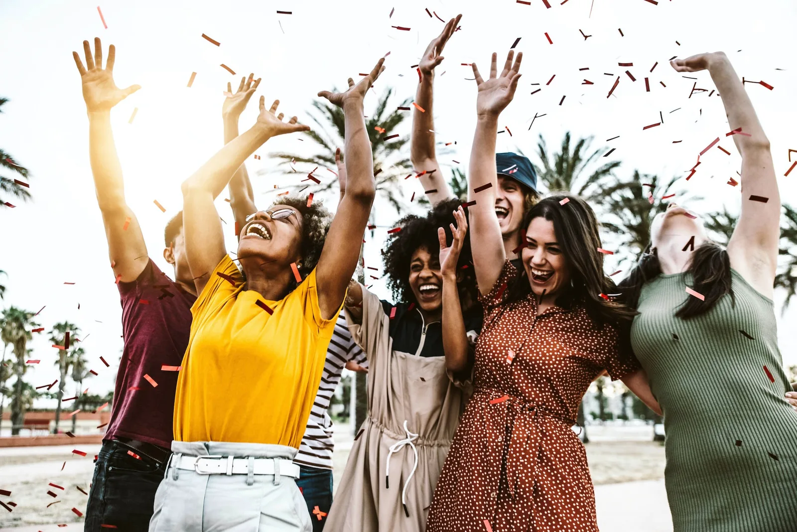 Group of friends enjoying party throwing confetti in the air